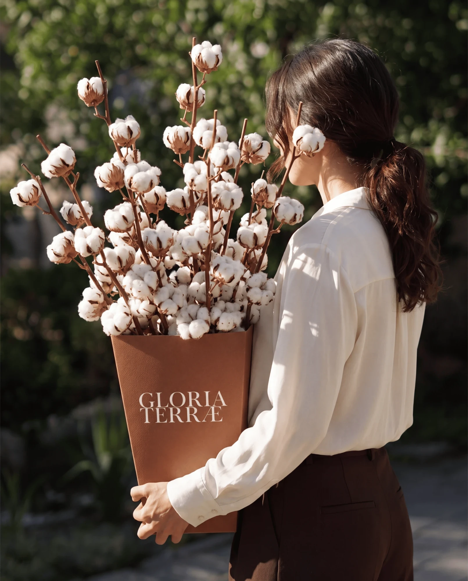 Donna che trasporta un box Gloria Terrae con bouquet di steli di cotone ornamentale